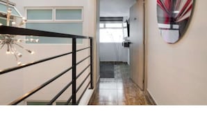 A hallway with a modern staircase, a ceiling light fixture, and a wall-mounted abstract artwork. - 3 Bedroom Balcony, 3 Hot Tubs, AC (Medellin)