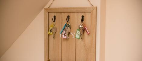 Een houten sleutelhanger aan de muur met sleutels en een 'POST'-bordje.