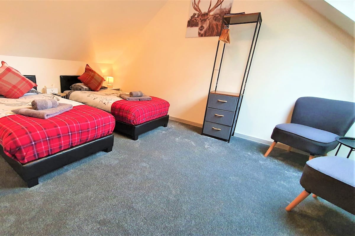 A hotel room with two beds, a desk, a chair, and a dresser.