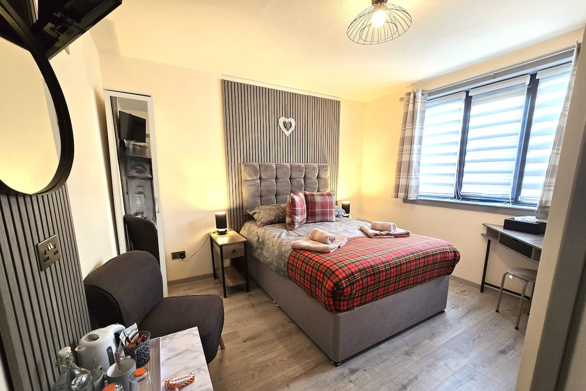 A modern bedroom with a large bed, a desk, and a chair.