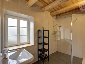 Une salle de bain avec une baignoire, une douche, une fenêtre et un plafond en bois.