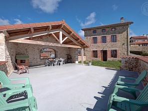 Un bâtiment en pierre doté d’un patio couvert, d’un espace extérieur aménagé pour s’asseoir et d’un mur en pierre.
