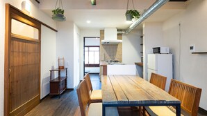 A modern kitchen with a wooden table and chairs, a hanging plant, and a refrigerator. - Jishoan (Kyoto)