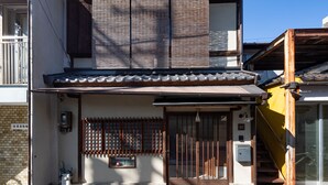 A traditional Japanese house with a tiled roof, a wooden gate, and a small window. - Jishoan (Kyoto)