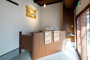 A reception desk with a wooden finish, a hanging light bulb, and a framed picture on the wall.