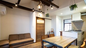 A modern kitchen with a wooden table and chairs, a built-in oven, and a hanging plant. - Jishoan (Kyoto)