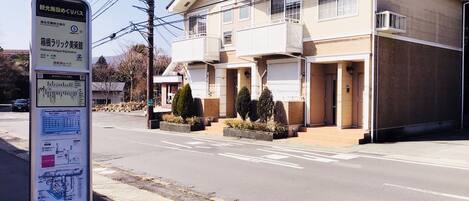 A two-story building with a flat roof, a balcony on the second floor, and a garage door.