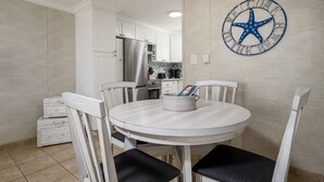 A dining area with a round table, white chairs, and a wall clock.