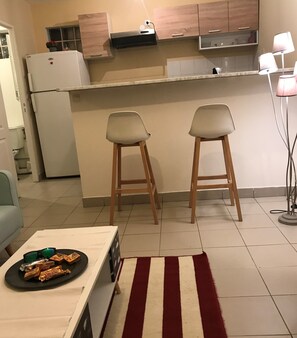 Compact kitchen area with a refrigerator, countertop, and table.