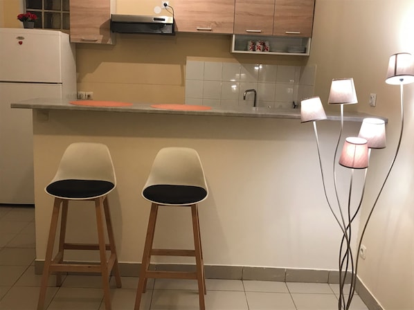 Modern kitchen with a heart-shaped refrigerator, oven, and microwave, featuring a sleek countertop and stylish bar stools.