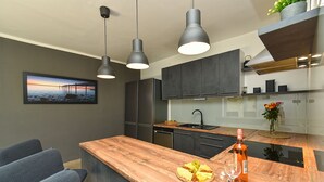 A modern kitchen with dark cabinets, a wooden countertop, and a built-in dishwasher. There is a painting on the wall and a vase with flowers on the counter. - Villa 2019/28699 (Istria - Poreč), 3000m from the beach (Poreč)