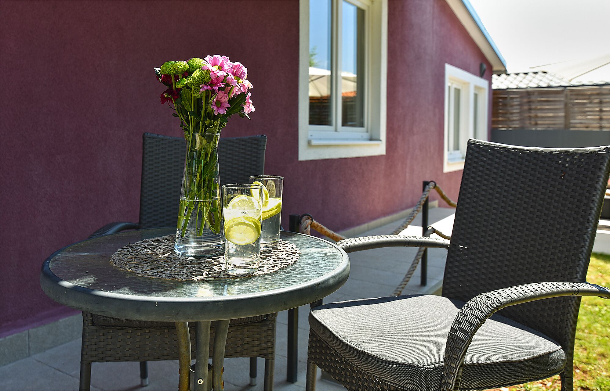 A round table with a vase of flowers and two glasses of water with lemon slices.