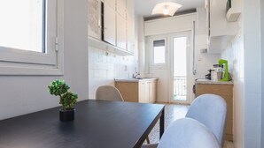 Cocina compacta con comedor, que incluye una mesa de madera oscura, sillas y una pequeña planta en maceta.