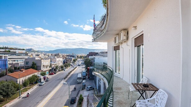 Un balcón con vistas a una calle de la ciudad, una mesa y una silla.