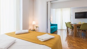 Una habitación de hotel con cama, escritorio, silla, televisor y sofá.