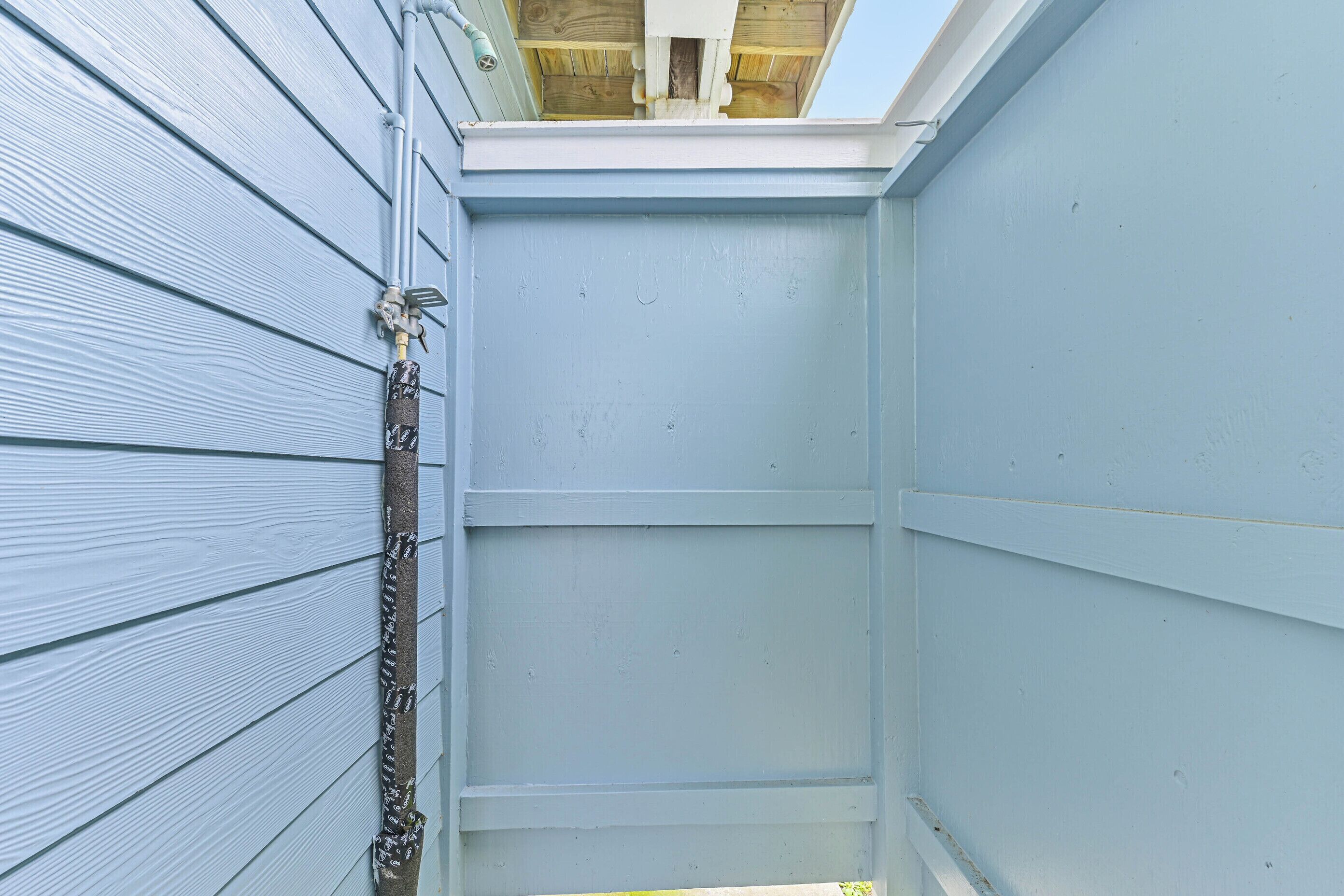 A narrow, enclosed space with light blue siding and a metal pipe running along the left side.