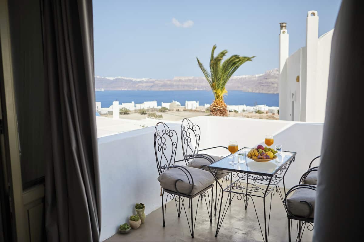 Ein Balkon mit einem Tisch für zwei Personen, mit einem Glas Orangensaft und einer Schüssel Obst.