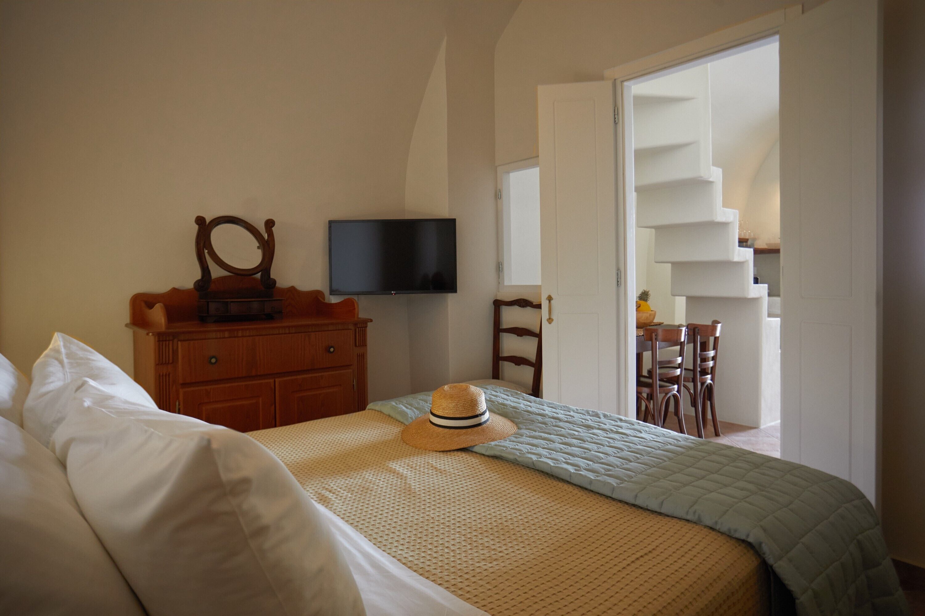A bedroom with a bed, a dresser, a television, and a staircase leading to another room.