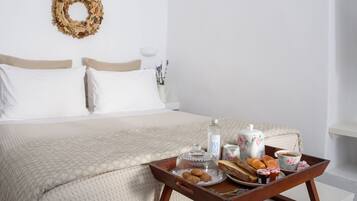A neatly made bed with a beige quilt, a tray with breakfast items, and a floral wreath on the wall.