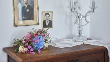 A wooden dresser with a bouquet of flowers, two framed photographs, and a crystal chandelier.