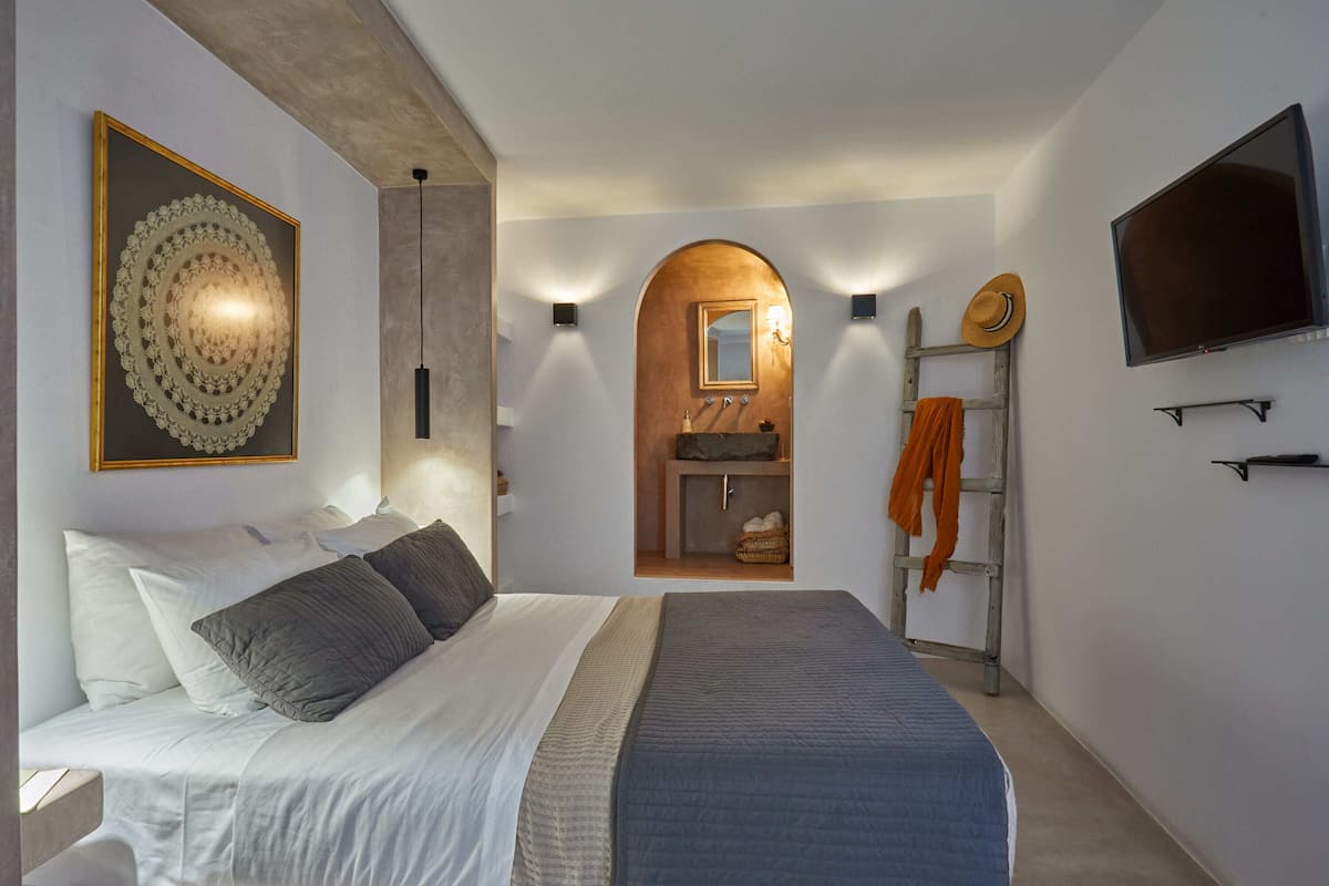 Ein Schlafzimmer mit einem Bett, einem großen gerahmten Kunstwerk, einem Schminktisch mit Spiegel, einem Fernseher und einer Leiter.