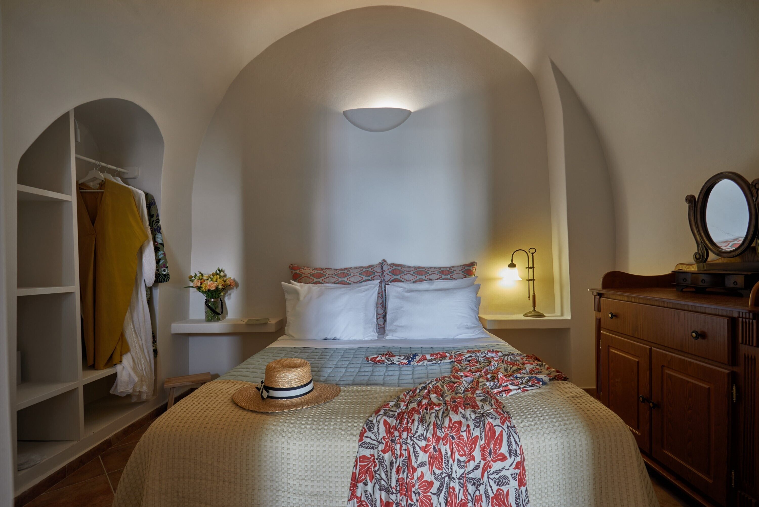 A bedroom with a bed, a wardrobe, a mirror, and a window with a light fixture.