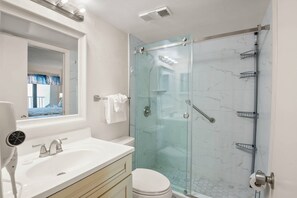Un baño con ducha de vidrio, un lavabo blanco y un inodoro.