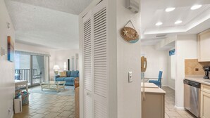 Un amplio espacio de estar con balcón, una cocina con electrodomésticos modernos y un comedor con una silla azul.
