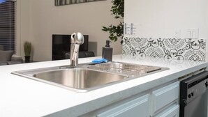 A modern kitchen with a stainless steel sink, a faucet, and a patterned backsplash. - Cozy condo near MCC, pool, covered parking (Mesa)