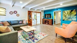 Een moderne woonkamer met een bank, fauteuil, salontafel en een televisie.