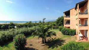 Un immeuble doté de balcons donnant sur un jardin et une plage.
