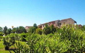 Un immeuble à étages, entouré d’une végétation luxuriante et d’arbres.