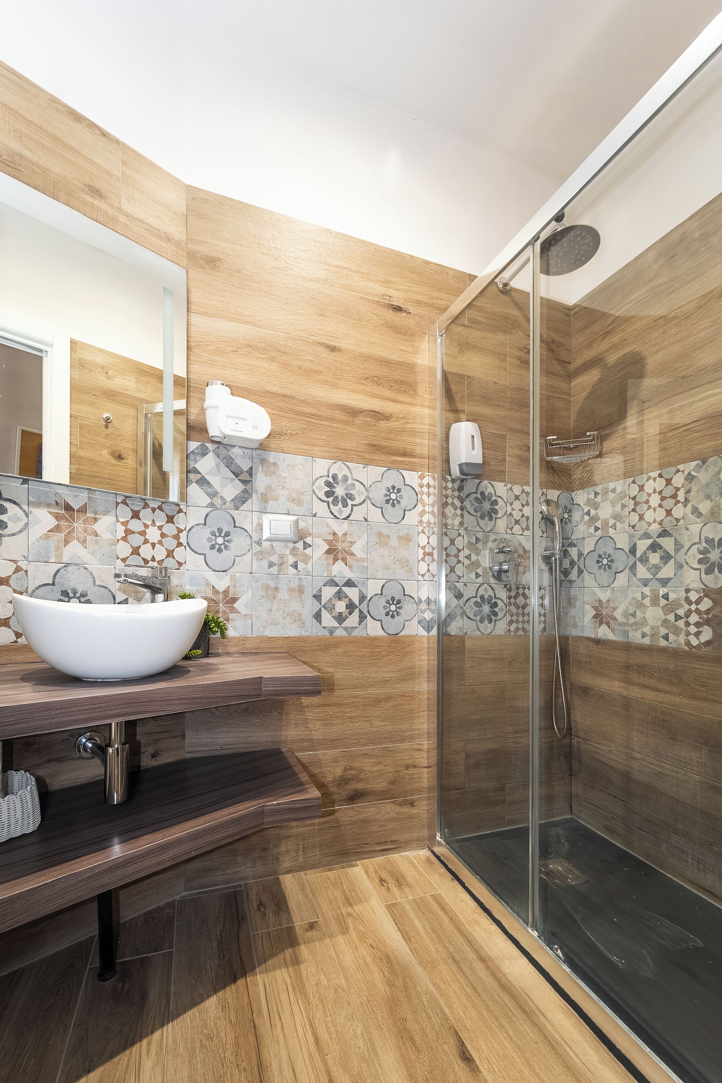 A modern bathroom with a glass-enclosed shower, a white vessel sink, and a wooden vanity.