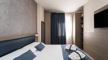 Habitación de hotel con una cama grande, televisión de pantalla plana, armario y espejo.