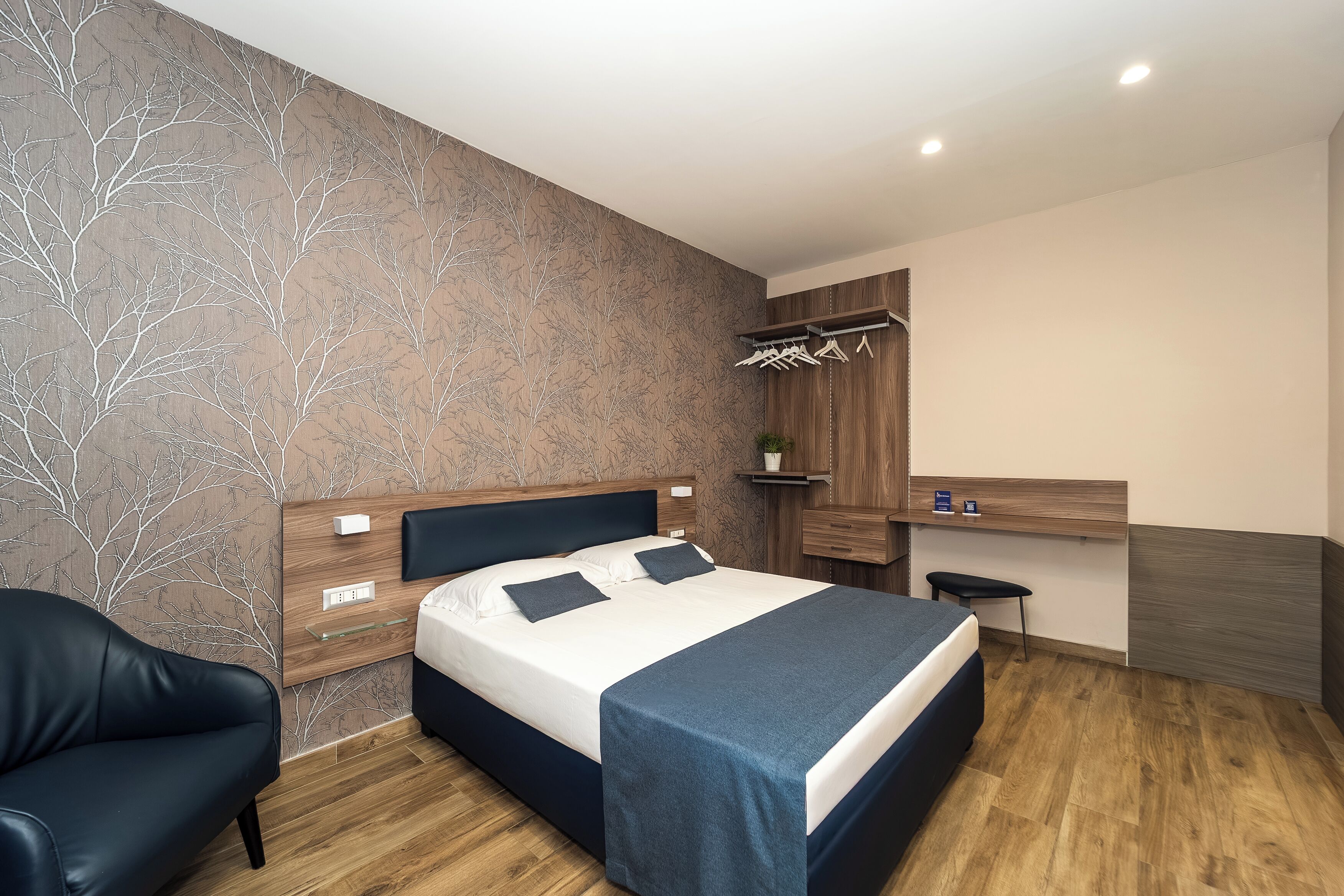 Een moderne slaapkamer met een bed, nachtkastje en een stoel.
