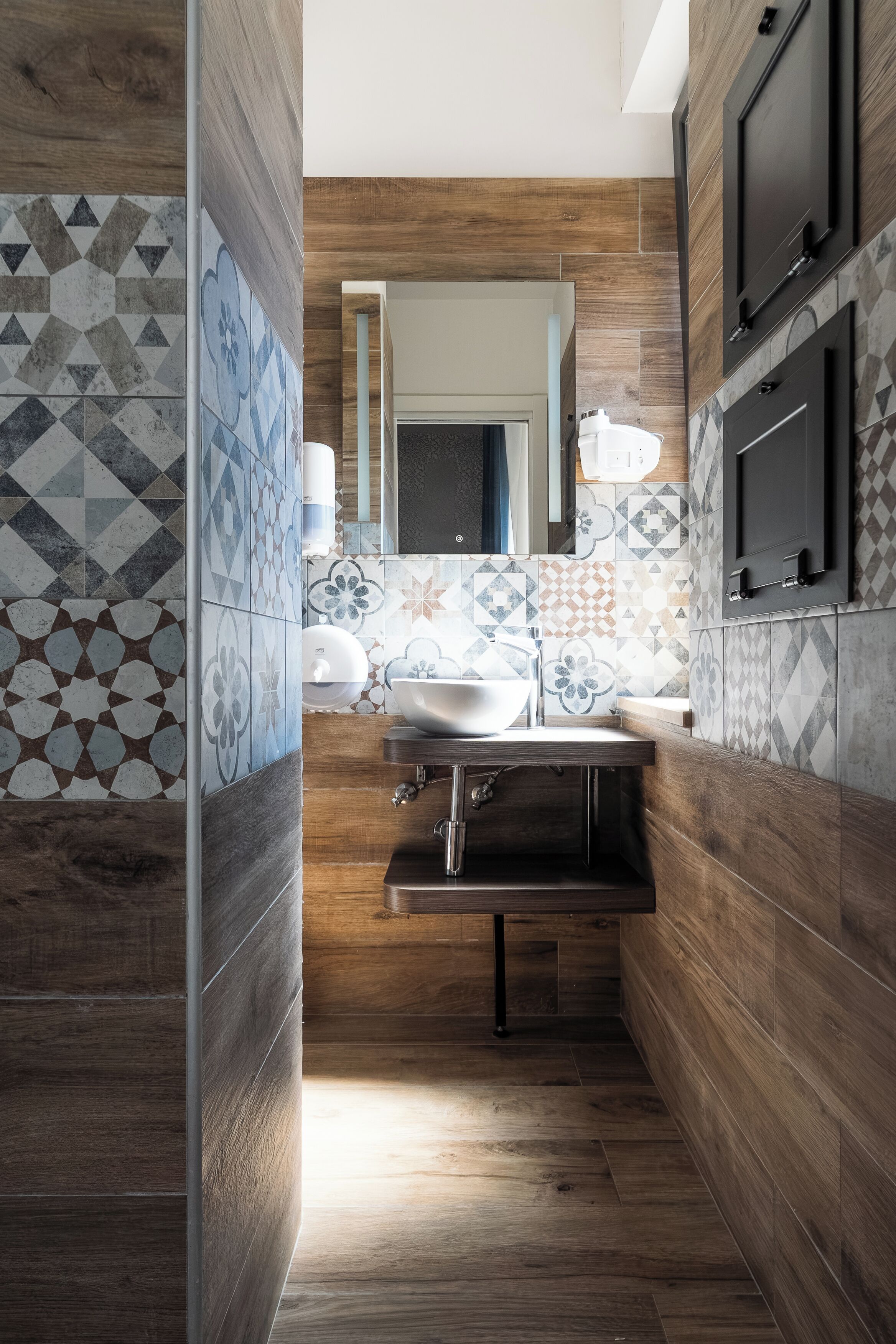A modern bathroom with a wooden floor, a sink, and a mirror.