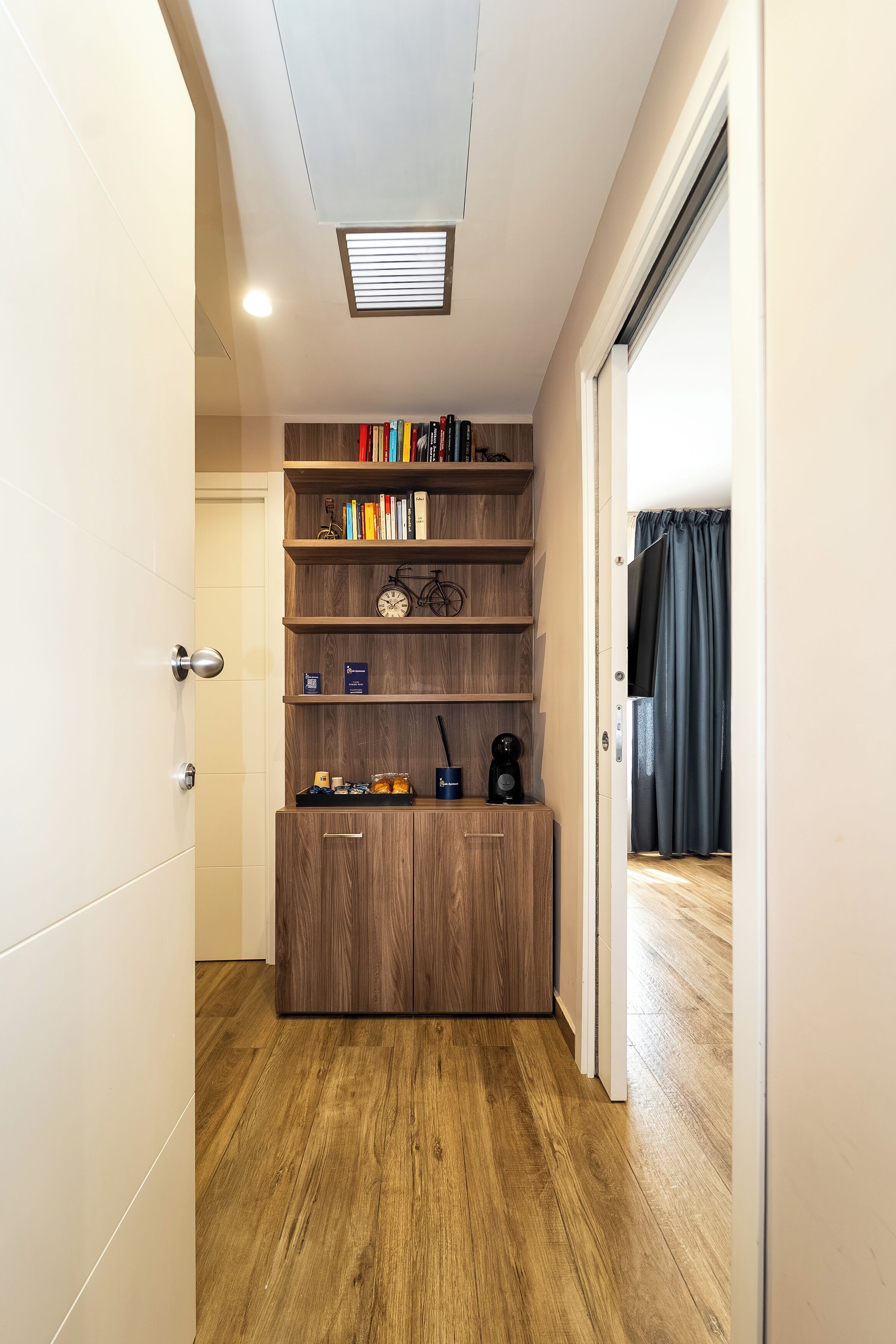 Un pasillo con una estantería de madera, una puerta y una ventana con persianas.