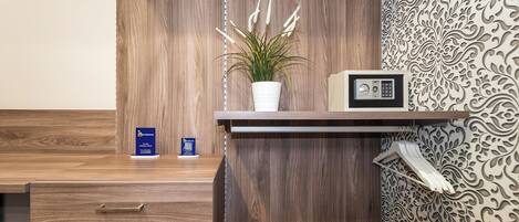 A wooden desk with a potted plant, a radio, and a blue booklet on the counter.