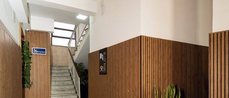 A hallway with wooden paneling, a staircase, and a potted plant.