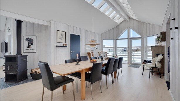 A spacious dining area with a high ceiling and large windows, a fireplace, and a view of the outside. - Beach front home in Tarm with sauna (Tarm)