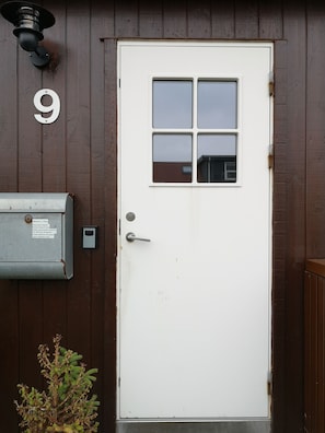 A white door with a small window, a mailbox, and a number '9' sign on a wooden wall. - Rose Cottage 70m2 Tórshavn with Parking (Hoyvík)