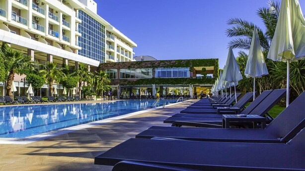 A hotel with a swimming pool, sun loungers, and palm trees. - Telatiye Resort Hotel (Alanya)