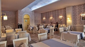 A restaurant with tables and chairs, a brick wall, and a skylight. - Telatiye Resort Hotel (Alanya)
