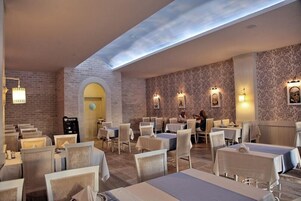 Um restaurante com mesas, cadeiras, uma parede de tijolos e um clarabóia.