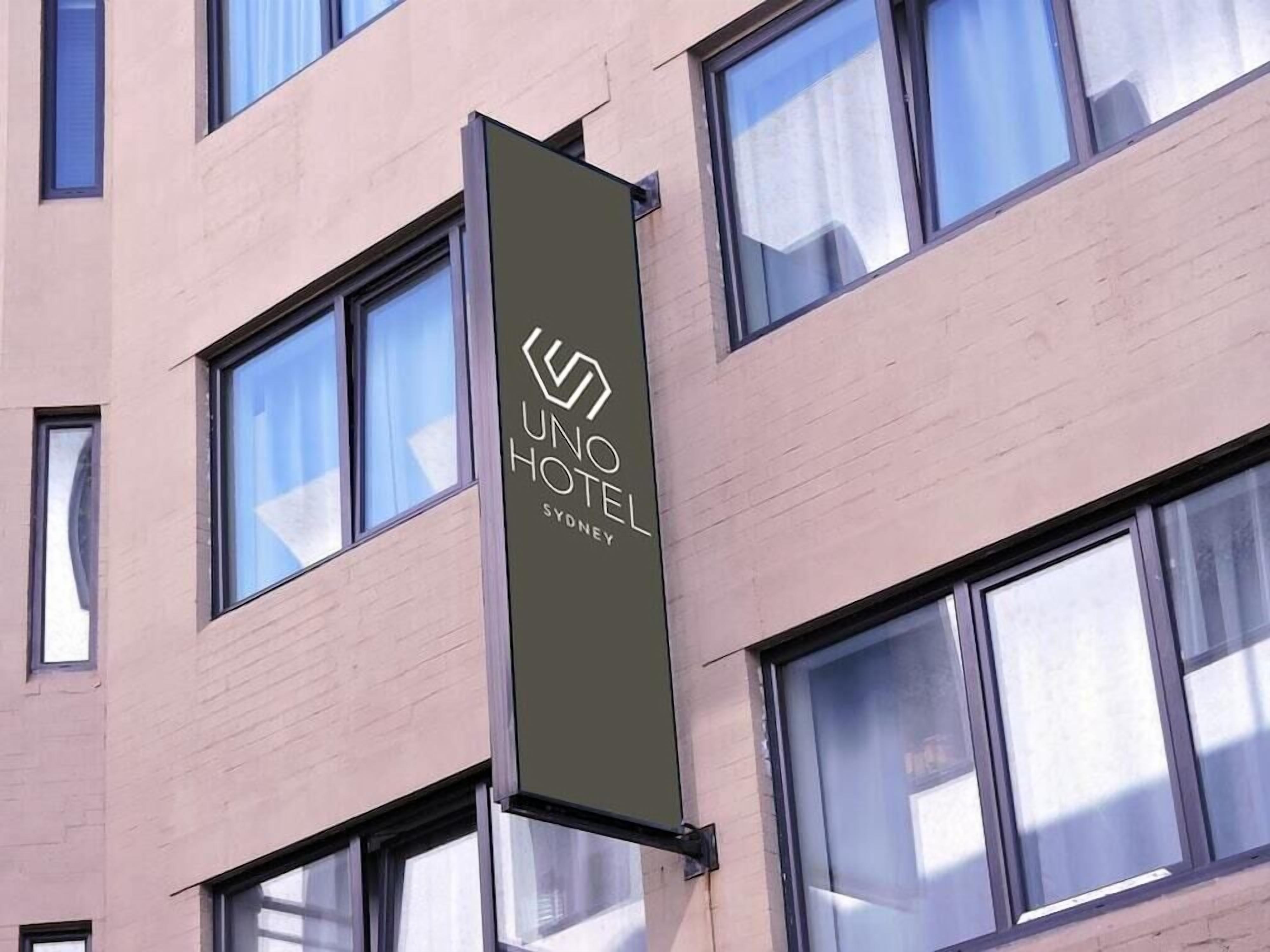 Un rètol d'hotel amb el nom "UNO HOTEL SYDNEY" a la façana d'un edifici.