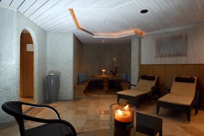A spa room with a checkered floor, a wooden bench, lounge chairs, and a table with a candle. - St Florian Hotel (Kaprun)