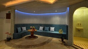 A spa area with a curved blue bench, a small table with candles, and a wooden bench to the right. - St Florian Hotel (Kaprun)