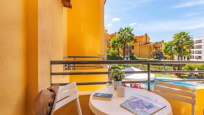 A balcony with a round table, white chairs, and a hat hanging on the wall. - Apartments Rio By Garvetur (Loulé)