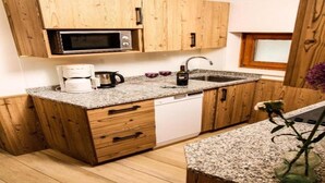 A kitchen with wooden cabinets, a microwave, a coffee maker, and a sink. - Pension Alpenrose (Kaprun)