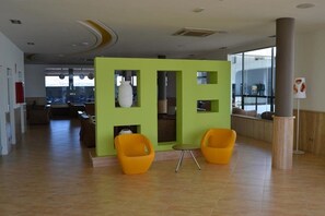 Um interior moderno com uma divisória verde, duas cadeiras amarelas e uma pequena mesa.